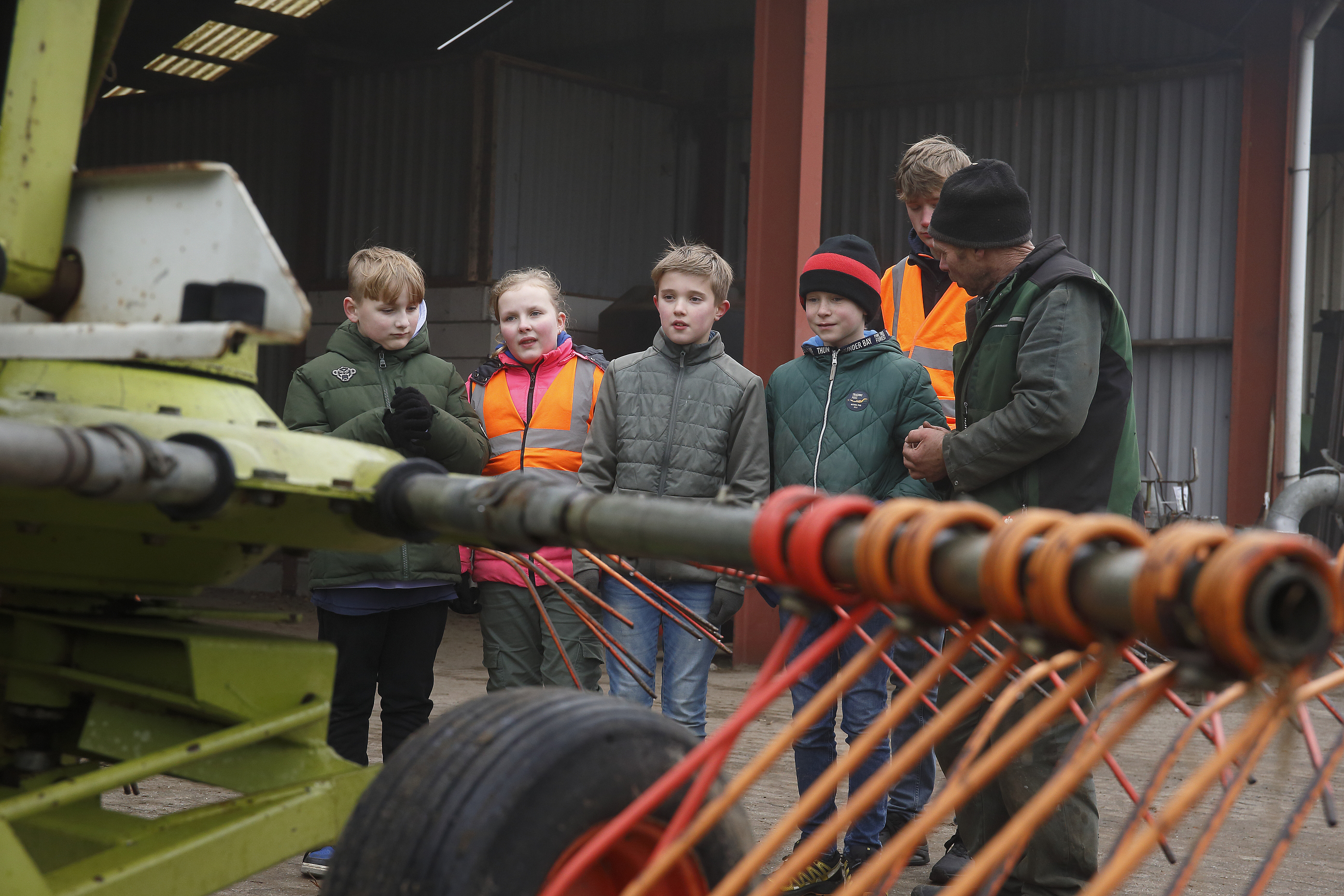 Scholieren krijgen uitleg en kijken naar een landbouwvoertuig